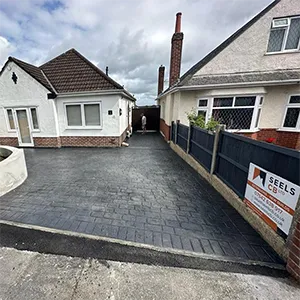 a house with a driveway and a fence in front of it