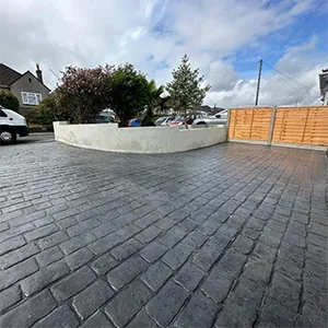 a brick driveway with a fence and a car parked in front of it
